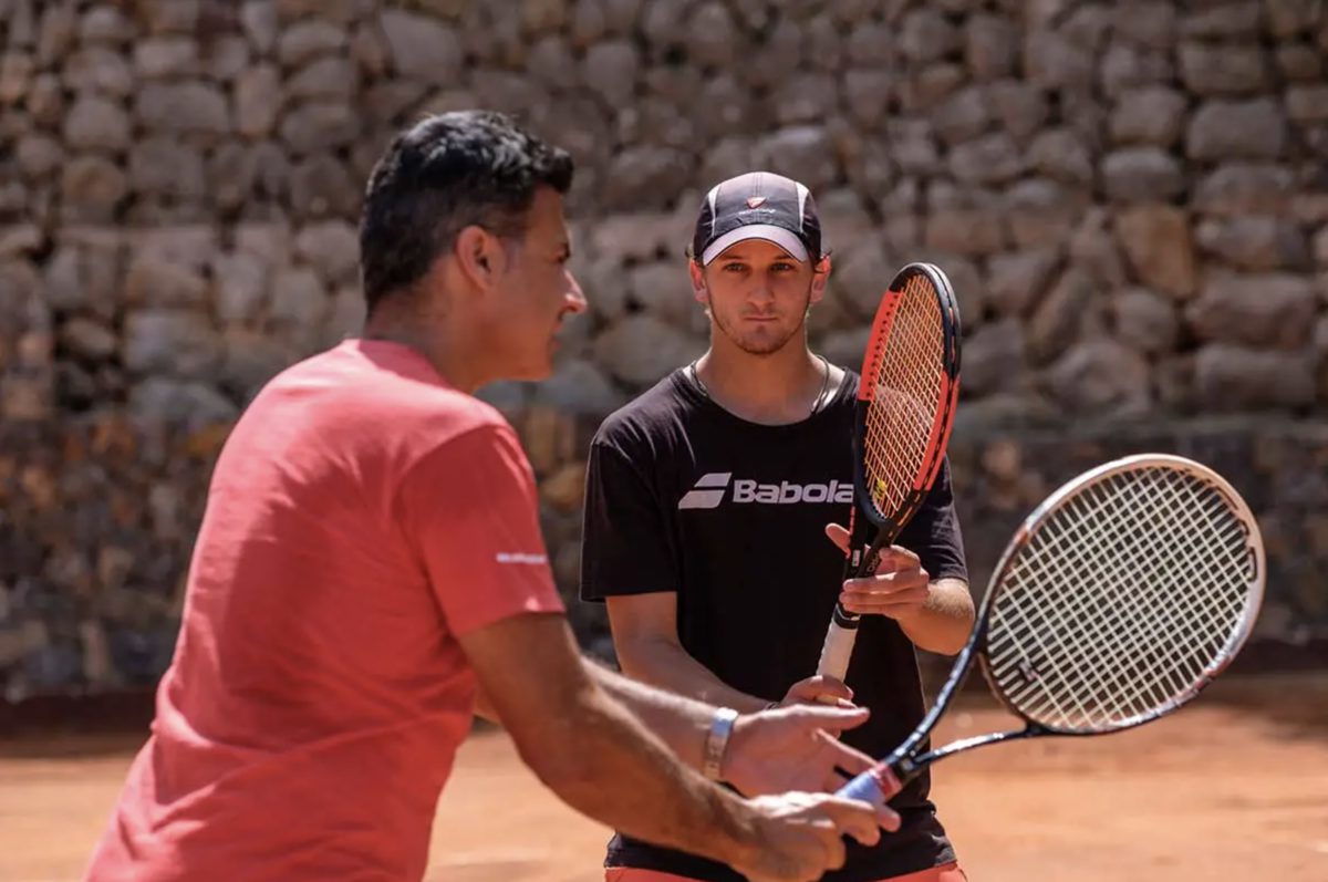 On-court coaching against the stone wall of the clay court