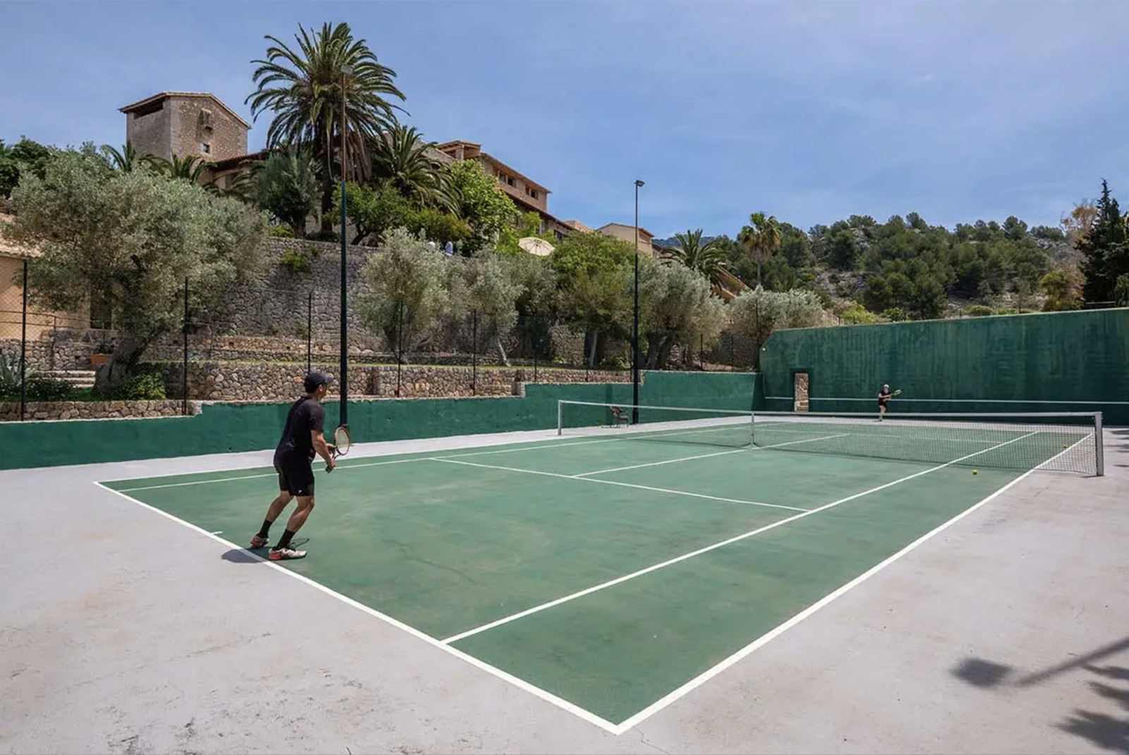 The hard court beneath the hotel, olive terraces behind